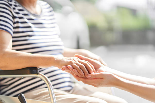 Hands Of Caregivers And Elderly People In Wheelchairs